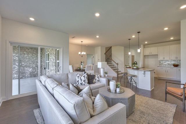 living room with a healthy amount of sunlight, dark wood-type flooring, and an inviting chandelier