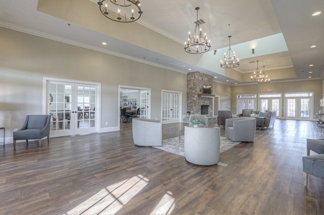 unfurnished living room featuring french doors, a high ceiling, dark hardwood / wood-style flooring, a tray ceiling, and a fireplace