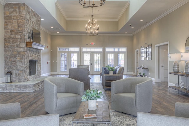 living room featuring a fireplace, french doors, a towering ceiling, and a chandelier