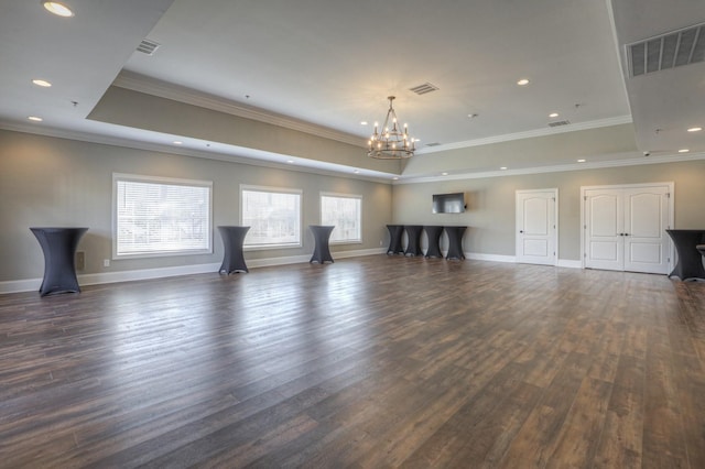 unfurnished living room featuring a tray ceiling, crown molding, dark hardwood / wood-style flooring, and a notable chandelier