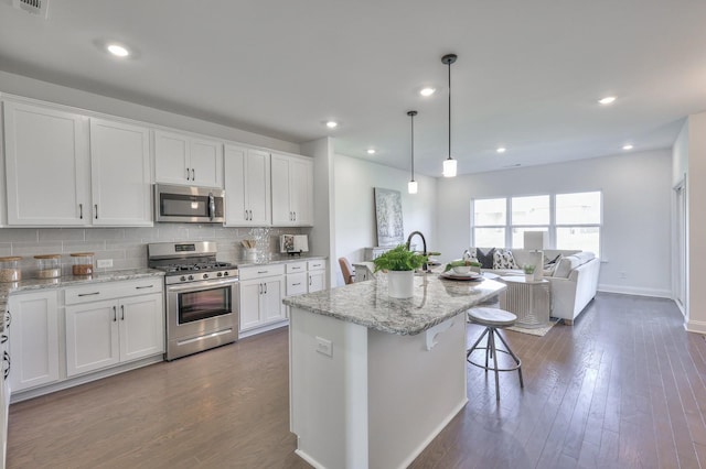 kitchen featuring a breakfast bar, white cabinetry, a center island with sink, and appliances with stainless steel finishes