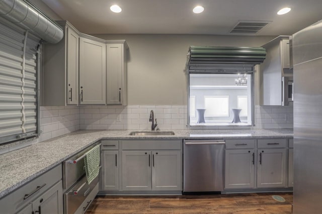 kitchen with dishwasher, dark wood-type flooring, sink, gray cabinets, and tasteful backsplash