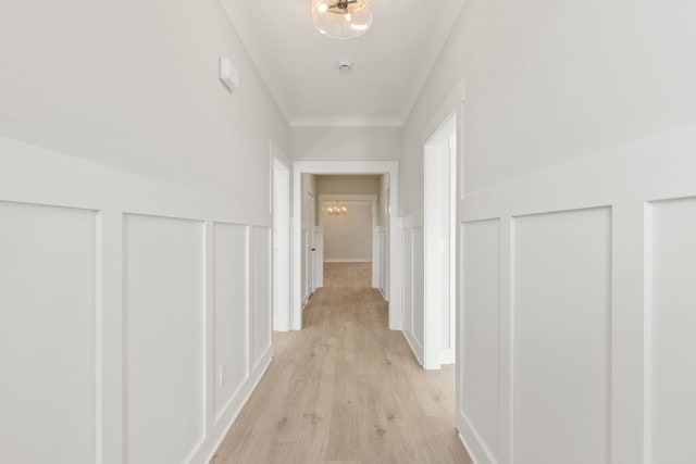 hallway with ornamental molding and light hardwood / wood-style flooring