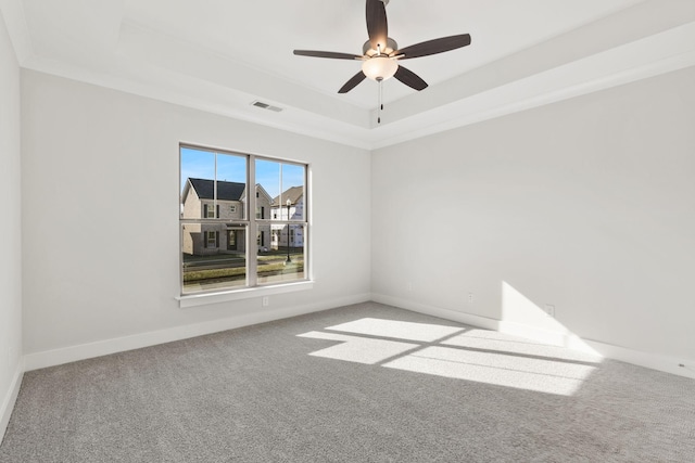 carpeted empty room with crown molding, ceiling fan, and a raised ceiling