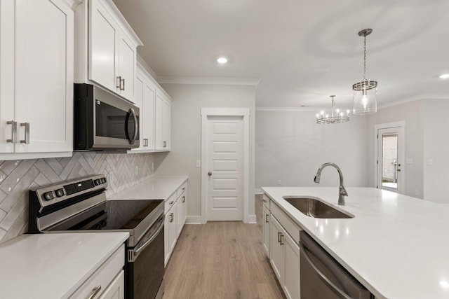 kitchen featuring sink, crown molding, pendant lighting, stainless steel appliances, and white cabinets