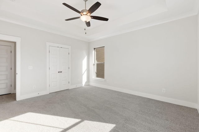 unfurnished bedroom featuring crown molding, ceiling fan, carpet, a raised ceiling, and a closet