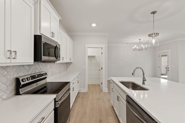 kitchen with sink, decorative light fixtures, ornamental molding, appliances with stainless steel finishes, and white cabinets