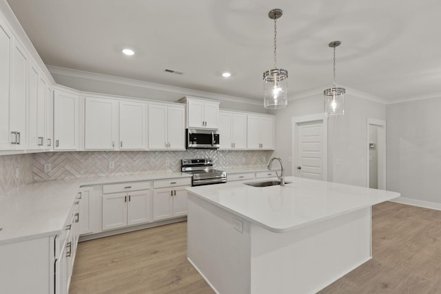 kitchen with white cabinetry, appliances with stainless steel finishes, sink, and a center island with sink