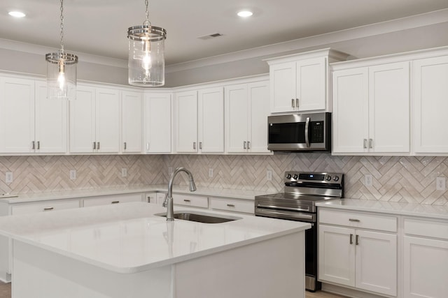 kitchen featuring sink, white cabinets, hanging light fixtures, stainless steel appliances, and a center island with sink