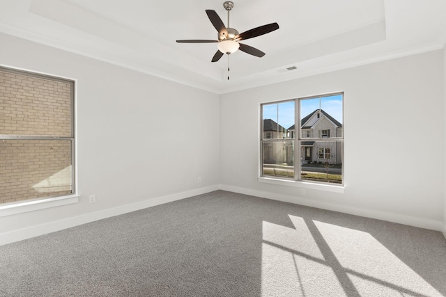 carpeted empty room with a raised ceiling and ceiling fan