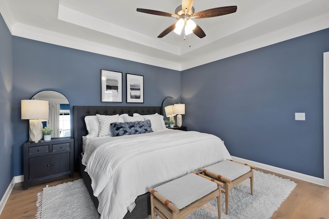 bedroom featuring a raised ceiling, ceiling fan, and light hardwood / wood-style flooring