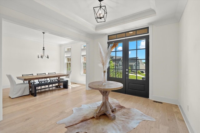 foyer with crown molding, french doors, a wealth of natural light, and a tray ceiling