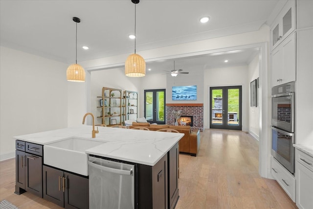 kitchen featuring decorative light fixtures, sink, white cabinetry, stainless steel appliances, and french doors