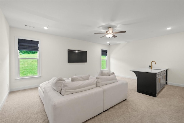 living room with ceiling fan, light colored carpet, and sink