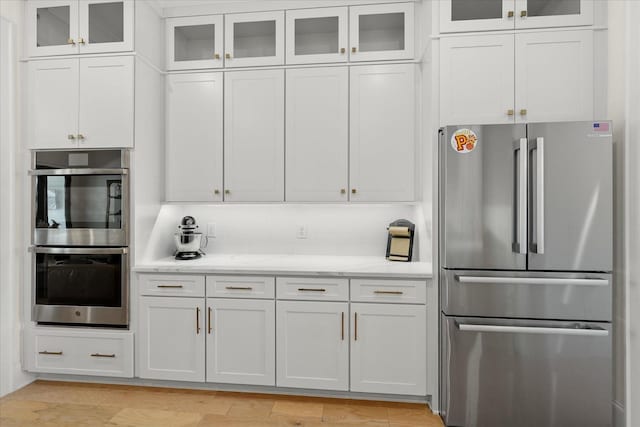 kitchen with light stone counters, white cabinetry, appliances with stainless steel finishes, and light hardwood / wood-style flooring