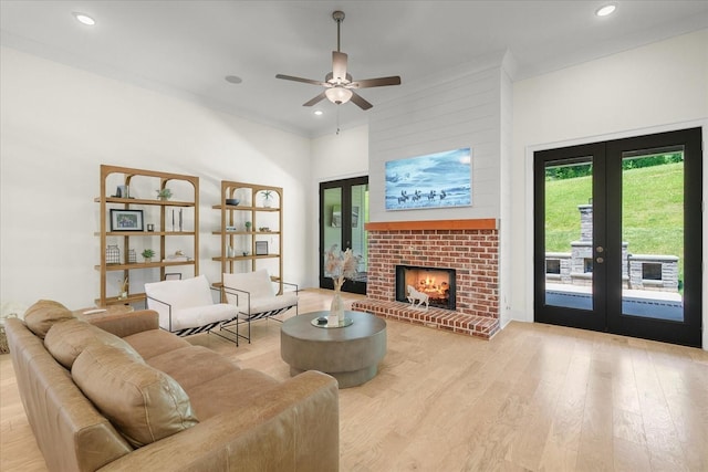 living room with ceiling fan, light hardwood / wood-style flooring, french doors, and a brick fireplace