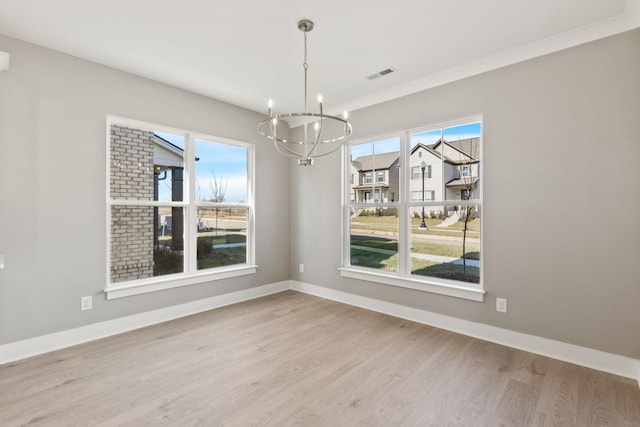 unfurnished dining area featuring ornamental molding, a chandelier, and hardwood / wood-style floors