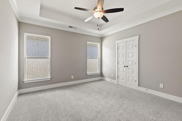 carpeted spare room featuring a raised ceiling and ceiling fan