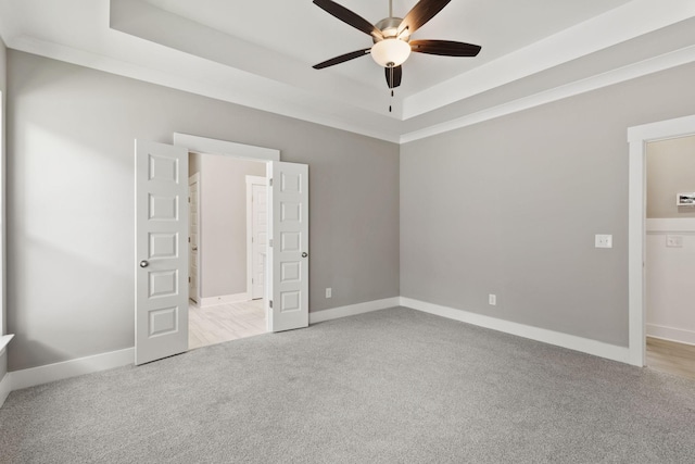 carpeted empty room with a raised ceiling and ceiling fan