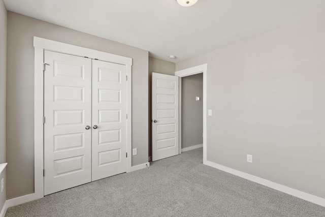 unfurnished bedroom featuring light colored carpet and a closet