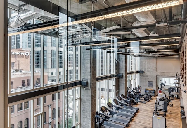 workout area with wood-type flooring and a towering ceiling