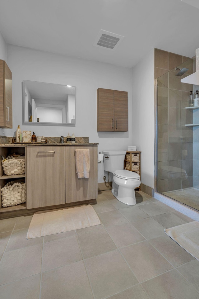 bathroom featuring vanity, a shower with door, toilet, and tile patterned floors