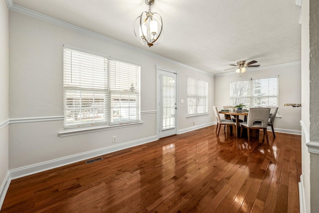 dining space featuring dark wood-type flooring, crown molding, and ceiling fan with notable chandelier