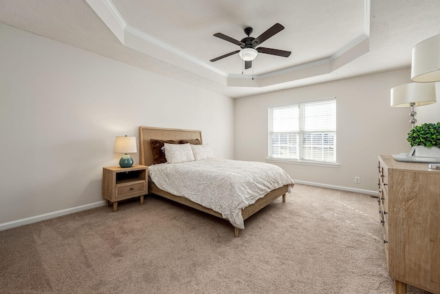 bedroom featuring ceiling fan, a tray ceiling, and light carpet