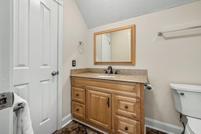 bathroom with vanity, toilet, vaulted ceiling, and a textured ceiling