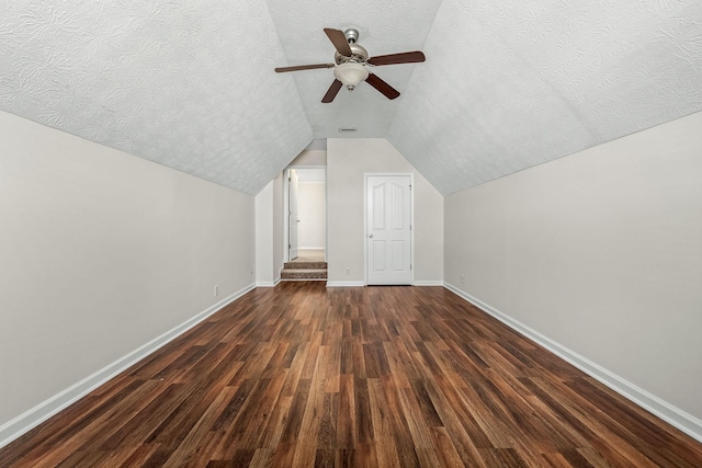 bonus room featuring lofted ceiling, dark wood-type flooring, and a textured ceiling