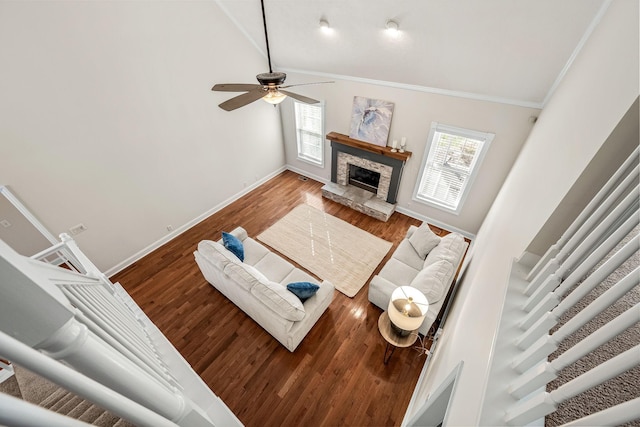 living room with crown molding, vaulted ceiling, ceiling fan, a fireplace, and hardwood / wood-style floors