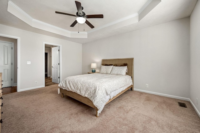 carpeted bedroom featuring crown molding, ceiling fan, and a tray ceiling