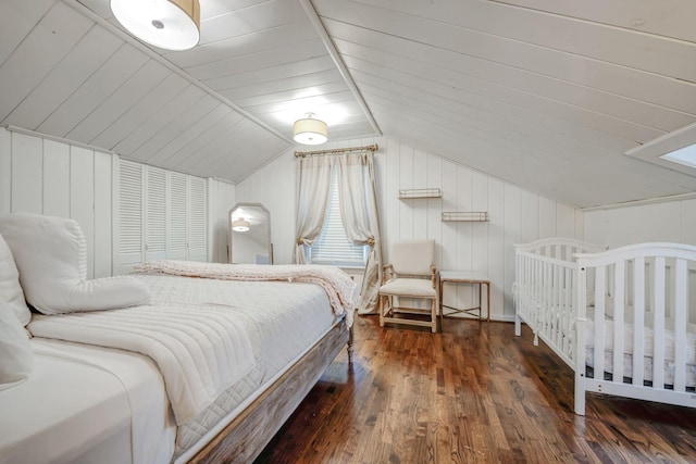 bedroom featuring lofted ceiling, a closet, dark hardwood / wood-style floors, and wooden walls