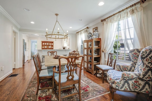 dining room featuring hardwood / wood-style floors, an inviting chandelier, and crown molding