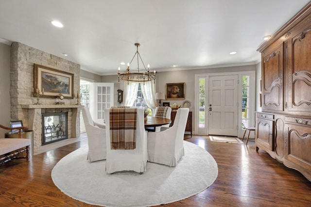 dining room featuring a notable chandelier, a fireplace, ornamental molding, and dark wood-type flooring