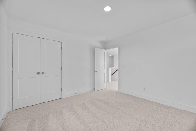 unfurnished bedroom with light colored carpet and a closet