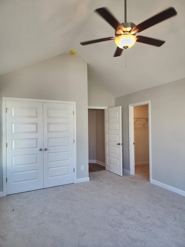 unfurnished bedroom with lofted ceiling, ceiling fan, a spacious closet, light colored carpet, and a closet