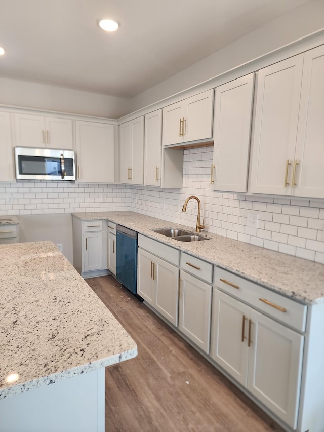 kitchen with wood-type flooring, white cabinetry, sink, light stone counters, and stainless steel appliances