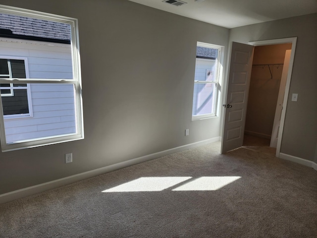 unfurnished bedroom with a closet, a spacious closet, and carpet