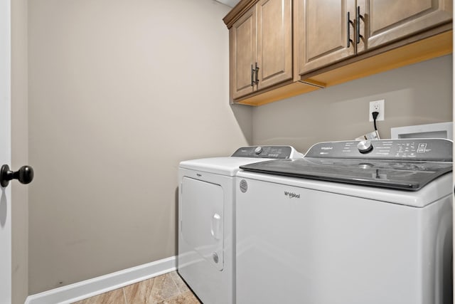 laundry room featuring washer and dryer and cabinets