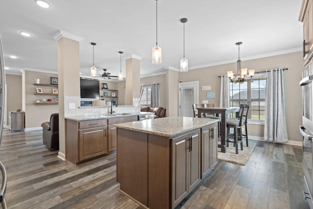 kitchen featuring light stone countertops, ceiling fan with notable chandelier, dark hardwood / wood-style floors, and hanging light fixtures