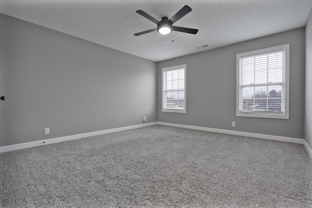 carpeted spare room featuring ceiling fan and a healthy amount of sunlight