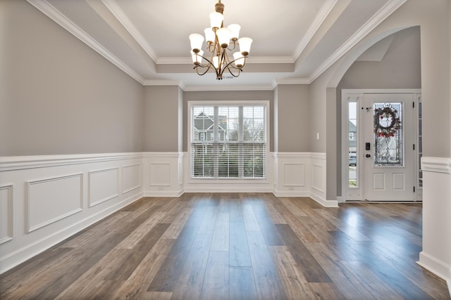 foyer with wood-type flooring, crown molding, a tray ceiling, and a chandelier