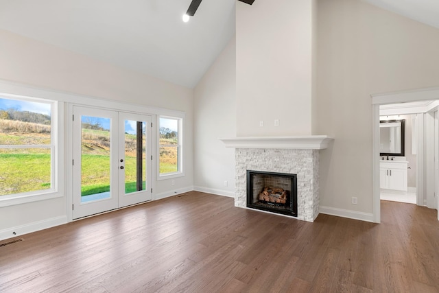 unfurnished living room featuring a fireplace, dark wood-type flooring, high vaulted ceiling, and a healthy amount of sunlight