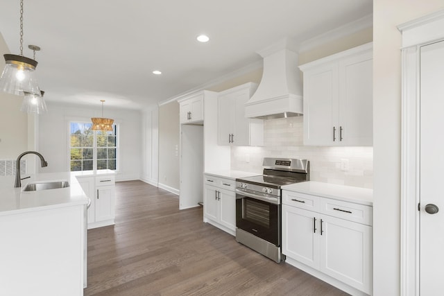 kitchen featuring stainless steel range, custom range hood, white cabinetry, and hanging light fixtures