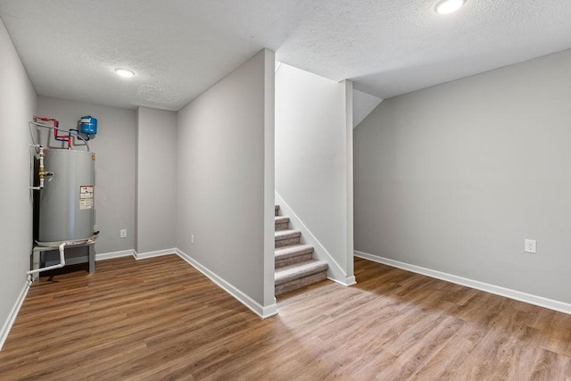 basement with wood-type flooring, a textured ceiling, and gas water heater