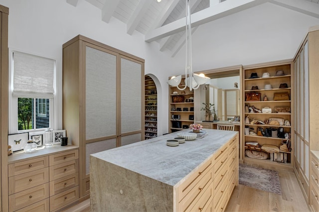 spacious closet featuring a chandelier, beam ceiling, high vaulted ceiling, and light hardwood / wood-style flooring