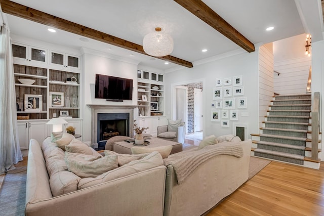 living room featuring beamed ceiling, light wood-type flooring, and built in features