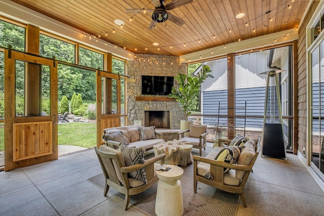 living room with ceiling fan, an outdoor stone fireplace, and wooden ceiling