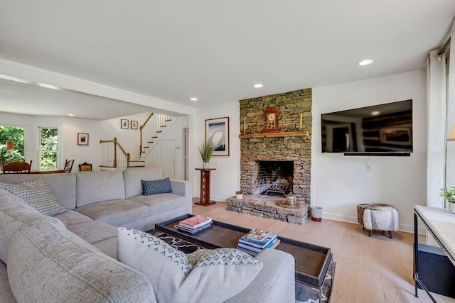 living room featuring a stone fireplace and light wood-type flooring